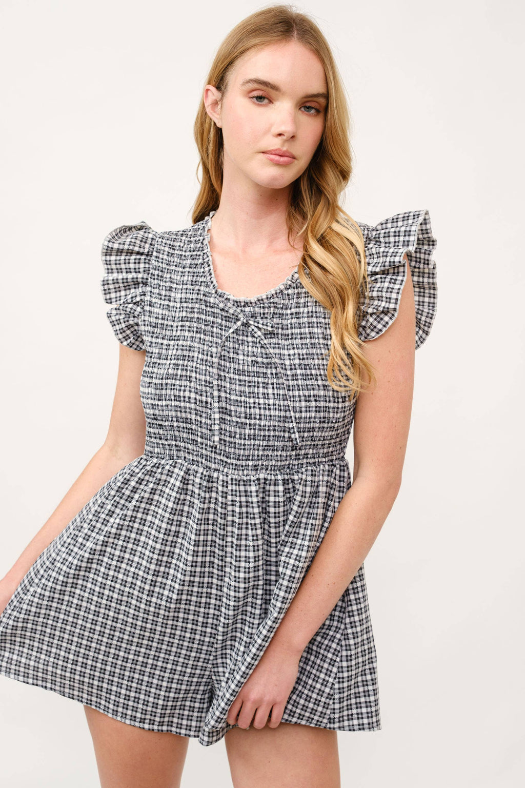 Woman wearing a checkered dress with ruffled sleeves on a white background