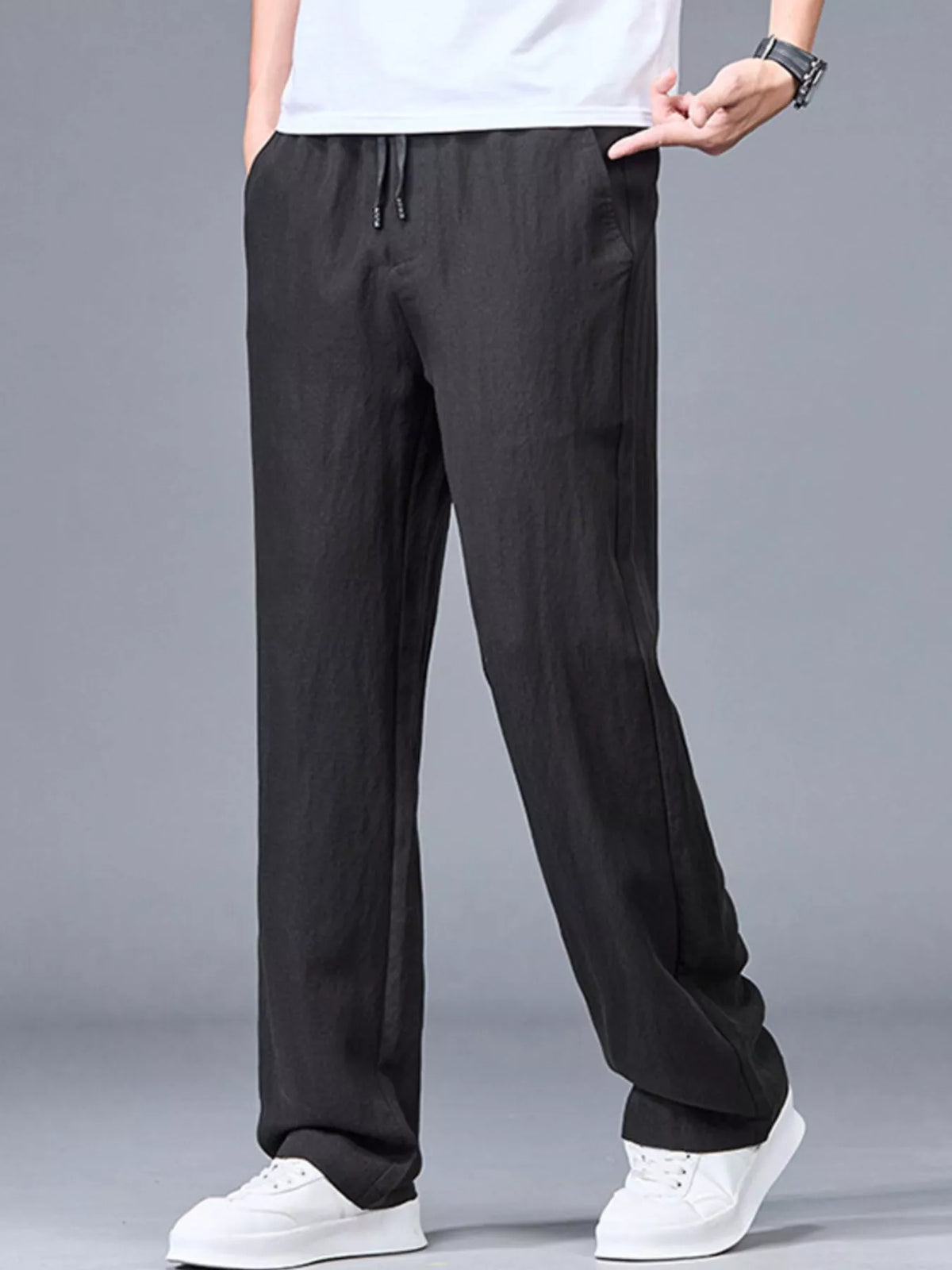 Person wearing relaxed wide-leg drawstring pants with elastic waistband and full-length straight legs with white background